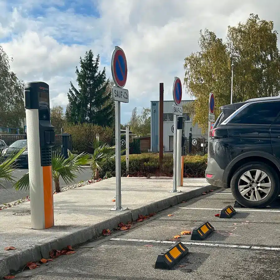 Bornes de recharge pour véhicules électriques ChargePoint installées sur un parking sécurisé avec signalisation "Sauf VE" et butées de stationnement.